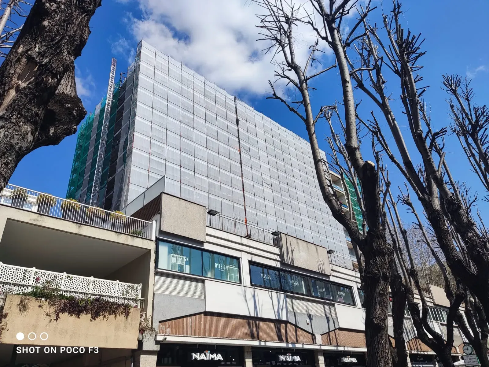 Edificio multipiano coperto da ponteggi e teli durante la riqualificazione della facciata.