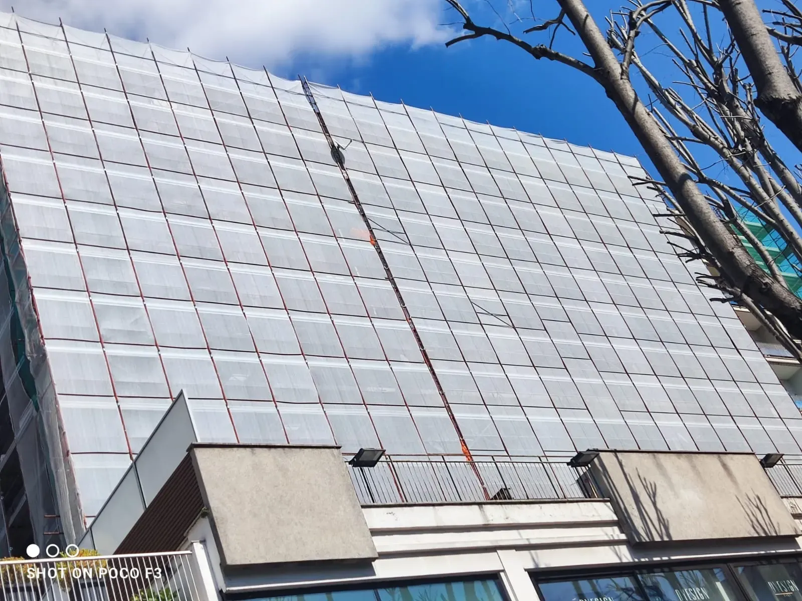 Facciata di un edificio multipiano con ponteggio e teli di protezione durante la riqualificazione.