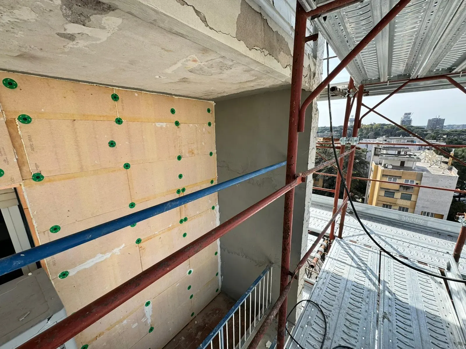 Pannelli isolanti del cappotto fissati con tasselli sulla facciata di un edificio.