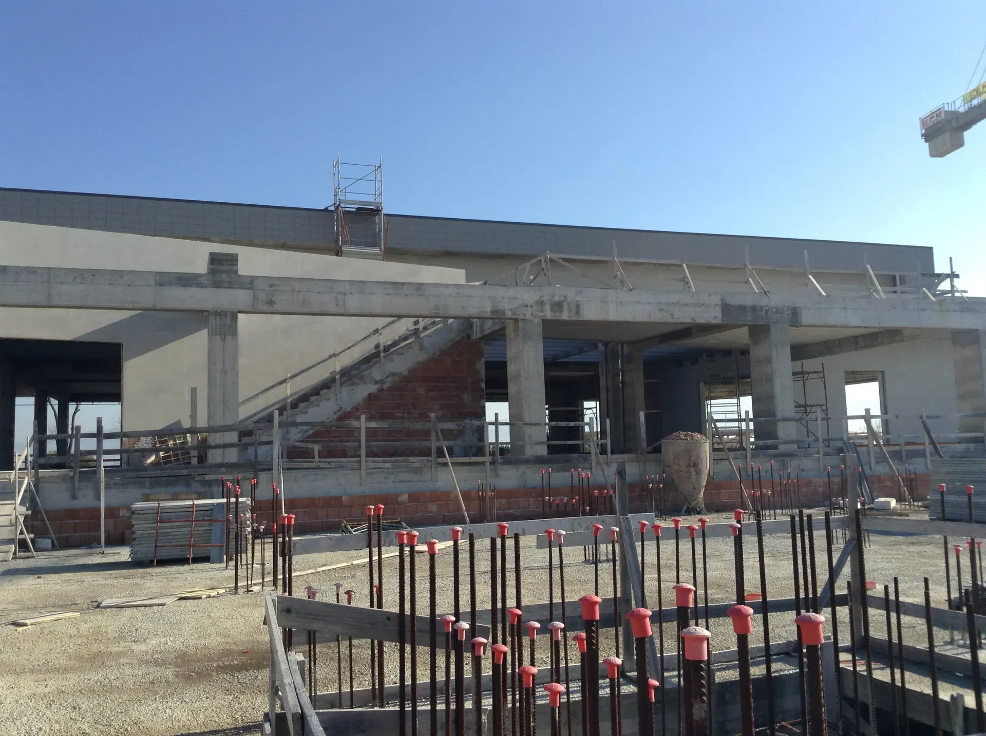 Struttura in cemento armato con i ferri di ripresa dei pilastri in primo piano.